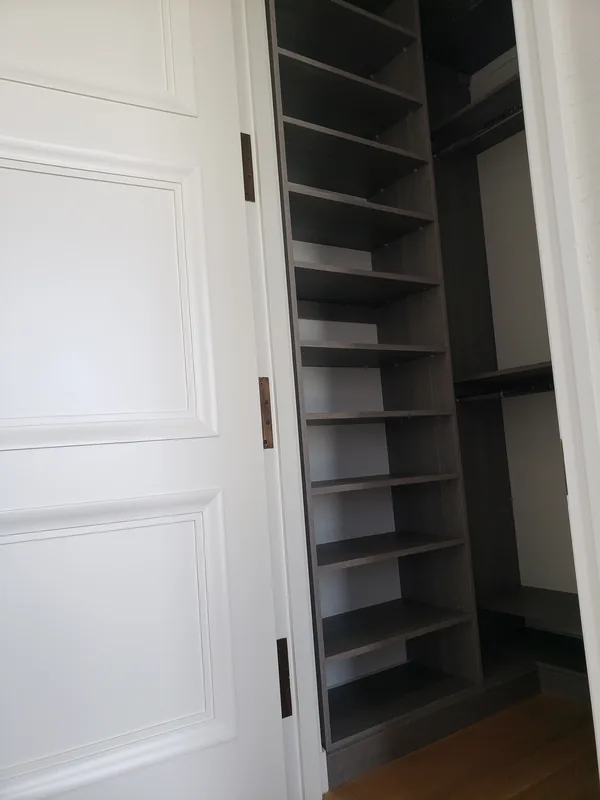 Dark gray reach-in closet with a tall adjustable shelf tower and hanging sections