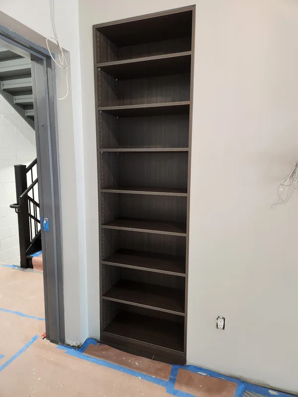 Tall dark wood-grain shelving fitted into a narrow wall recess