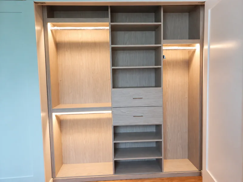 Two-tone wardrobe with illuminated hanging sections, central shelves and two drawers