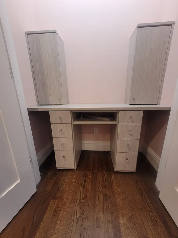 Compact light wood-grain desk fitted into a recess with two drawer pedestals, a center shelf and two wall cabinets with clear round knobs