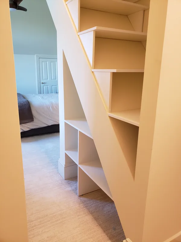White closet shelving arranged around the diagonal shape of a sloped ceiling