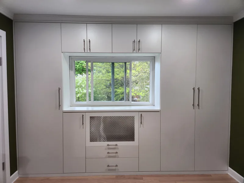 White built-in wardrobe surrounding a window with doors, drawers and a central display compartment