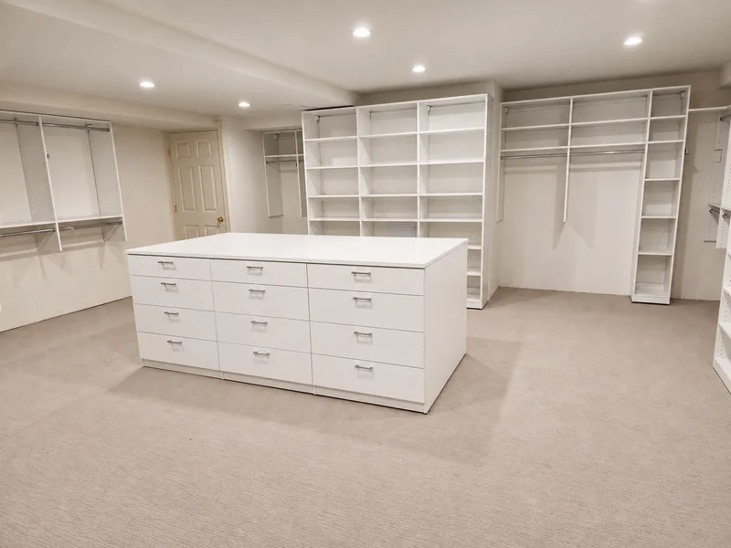 White walk-in closet with a twelve-drawer island, adjustable shelves and hanging rails